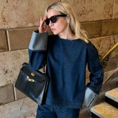 an influencer wears a dark denim short, black sunglasses, and a black bag