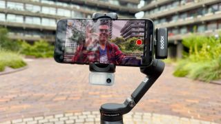 Hohem iSteady V3 gimbal being used to film a person on an iPhone