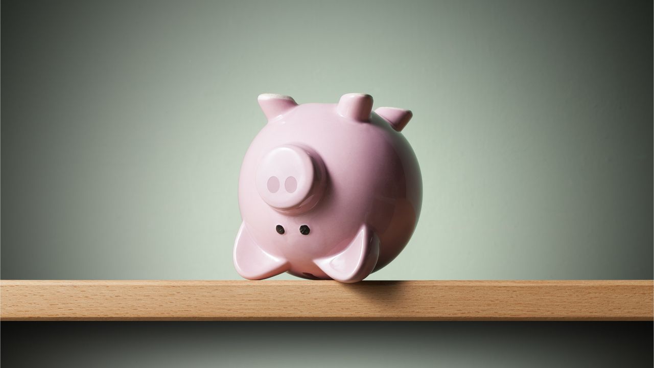 A pink piggy bank sits upside down on a table.