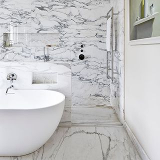 main bathroom with oval bath and sea of marble tiles