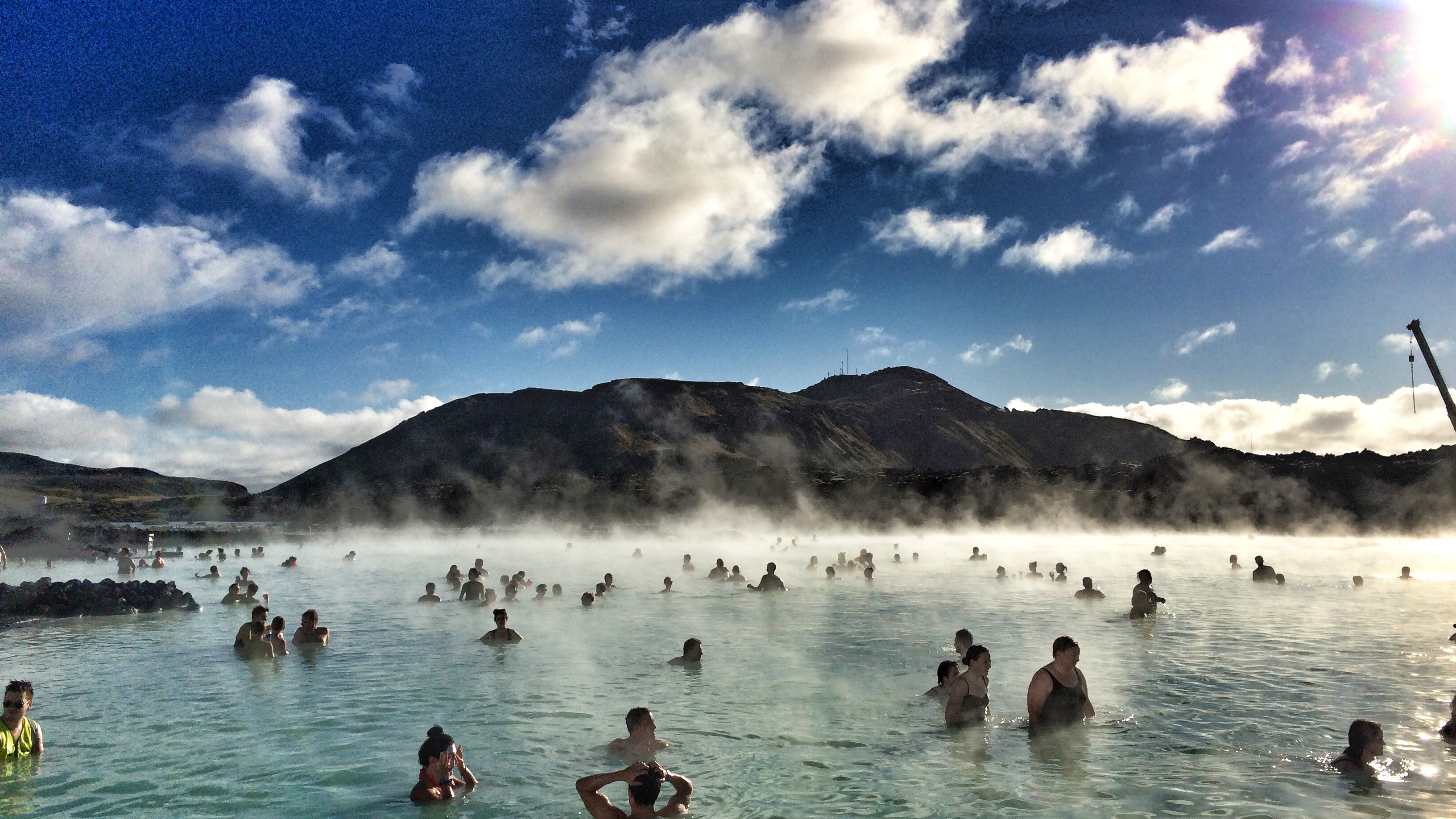 A public thermal pool with towels hanging on rails and light blue water with dramatic cloudscape in Mývatn, northern Iceland.