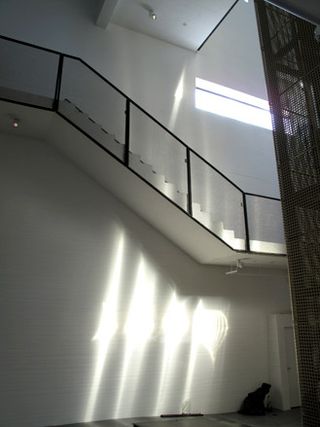 Hearning Museum of Contemporary Art by Steven Holl, Denmark. A high white wall with a staircase with glass railings going up it.