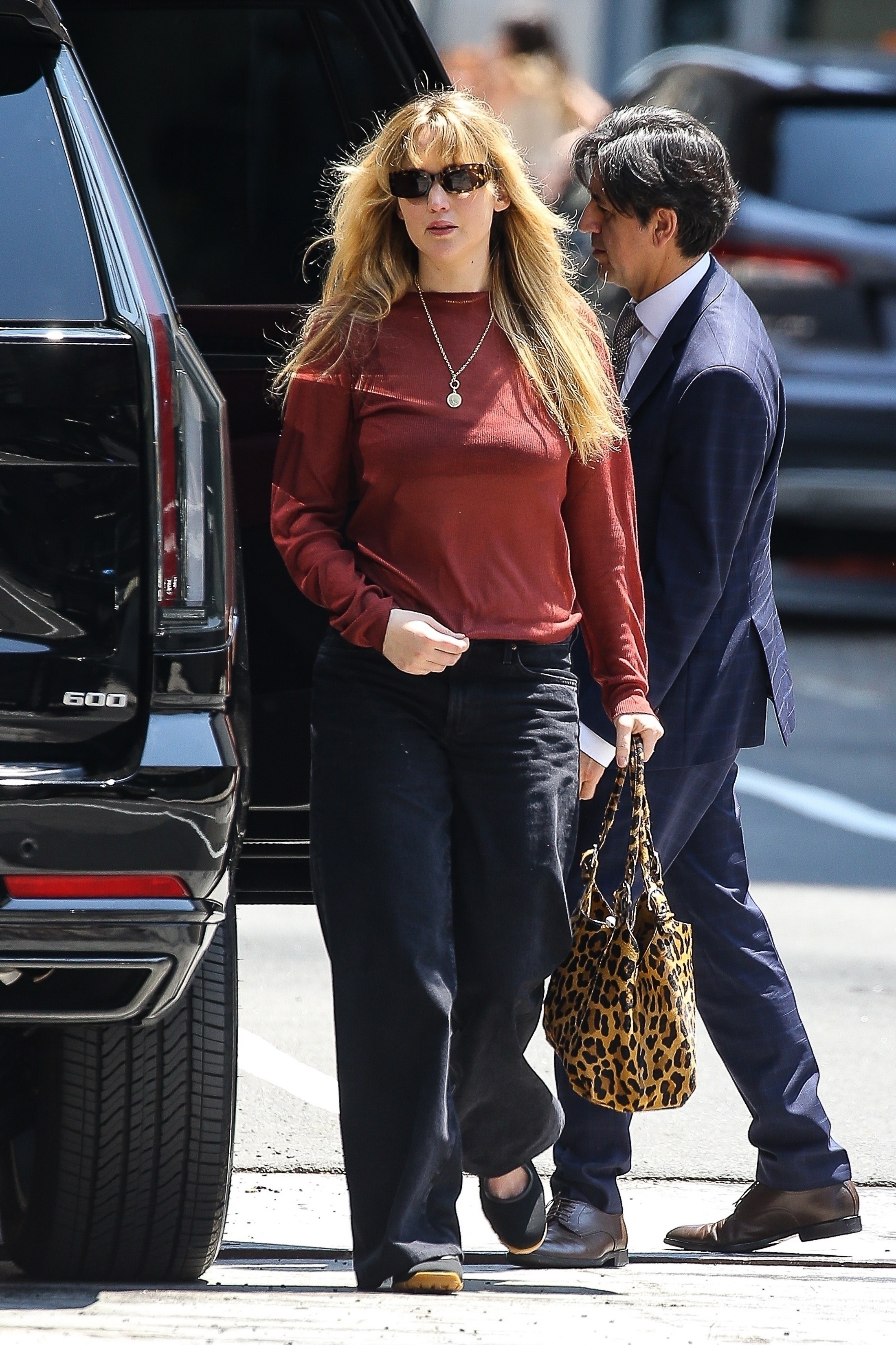 Jennifer Lawrence wearing black Wales Bonner Mary Jane sneakers with jeans and a red top