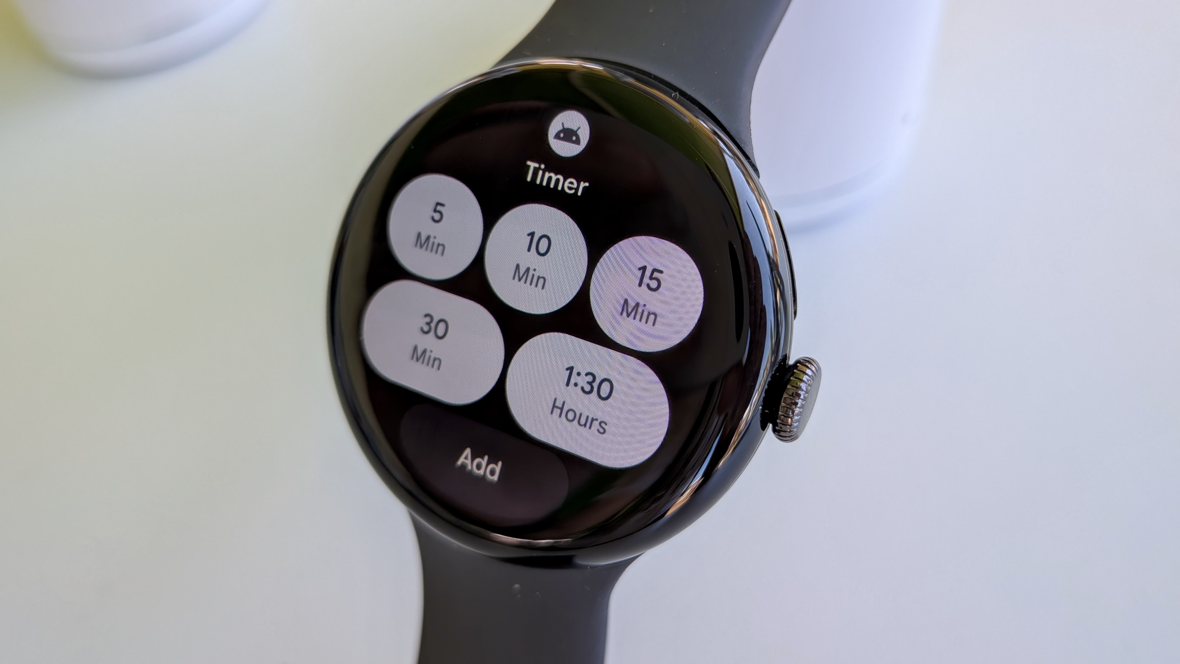 The new Timer tile on Wear OS 6 on the Pixel Watch 3, showing default buttons for 5, 10, 15, and 30 minute and 1:30 hour timers, plus an Add button
