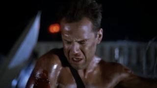 Bruce Willis as John McClane cautiously looking down from the Nakatomi Plaza rooftop in Die Hard