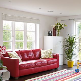 white living room with red sofa and potted plants