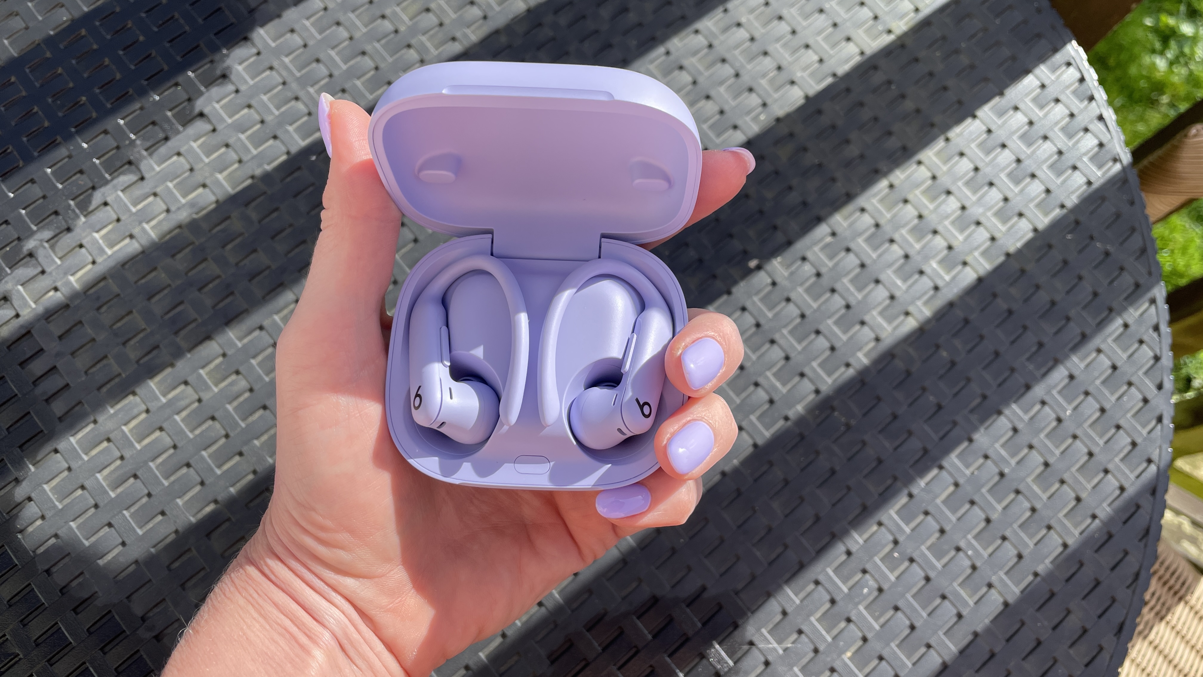 Beats Powerbeats Pro 2 held in a woman's hand with perfectly-matching nail polish