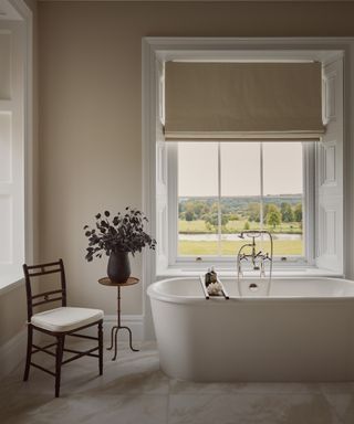 Neutral painted bathroom with large window and freestanding bath