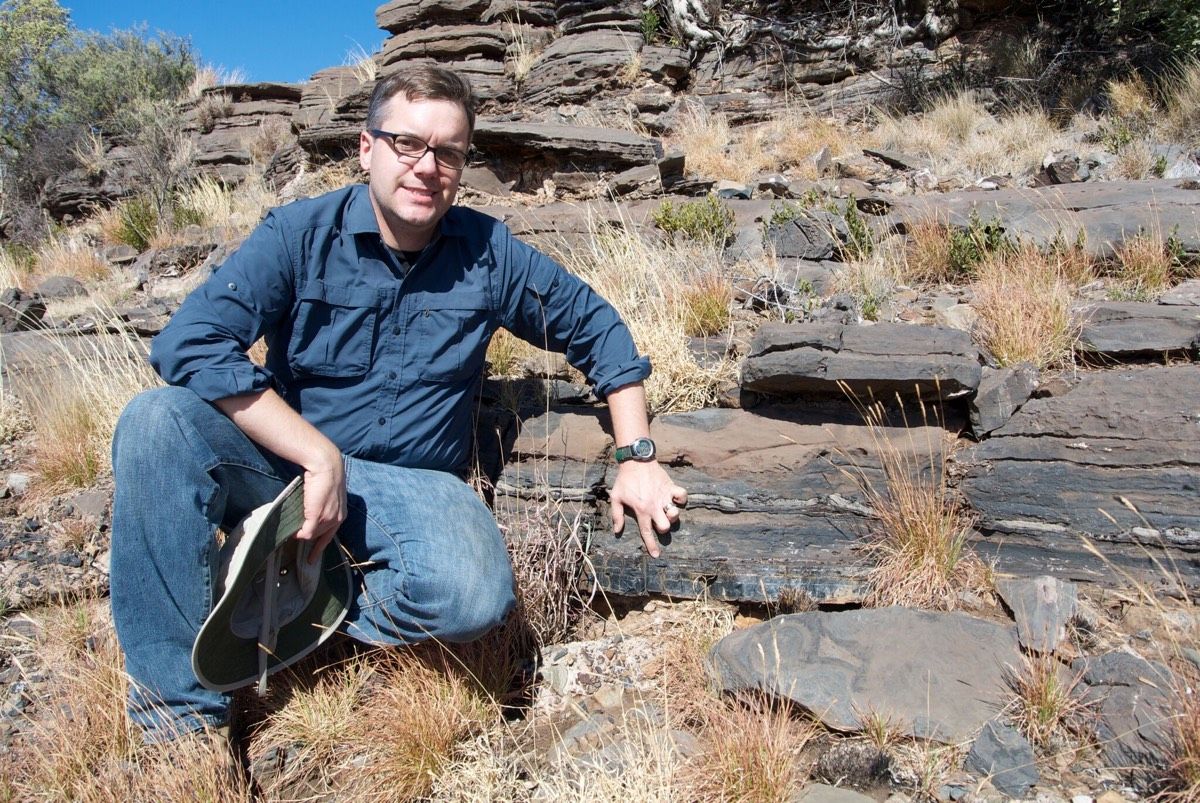 University of Cincinnati geologist Andrew Czaja points to a section of black chert in Northern Cape province, South Africa, where microscopic fossils that may be the oldest known sulfur oxidizers were found. The bacteria lived 2.52 billion years ago. 