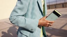 Google Pixel 6 phone being held by a man in a light grey jacket