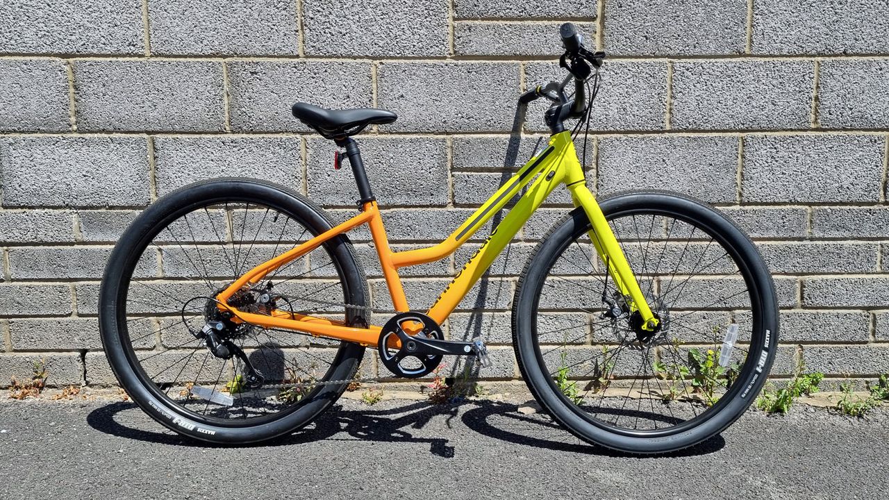 A pack shot of a bright yellow and orange bicycle with a step through frame