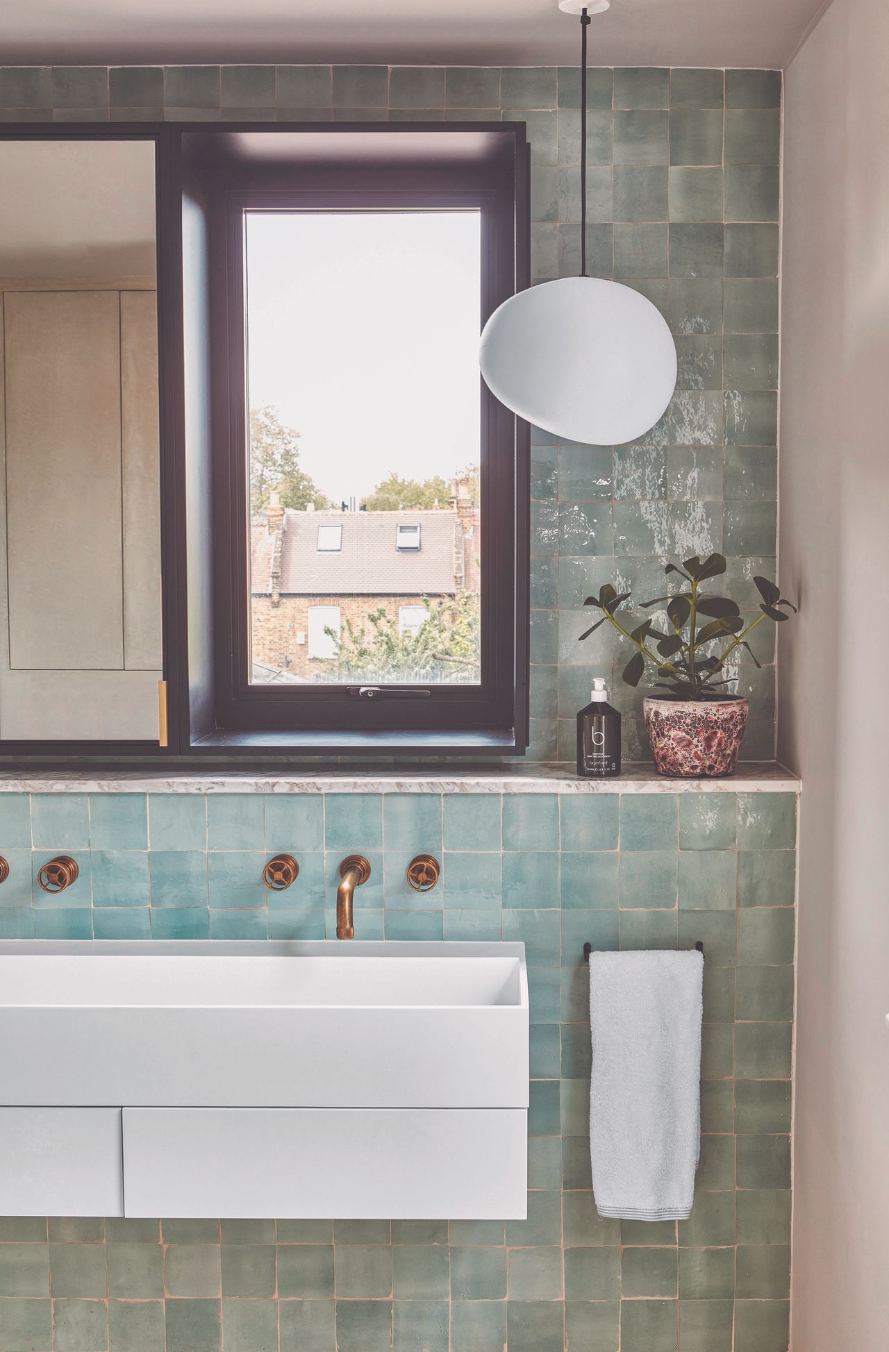 A blue tiled bathroom with a feature light and double sink