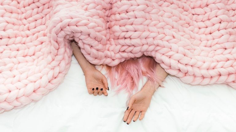 woman sleeping under a blanket with pink hair