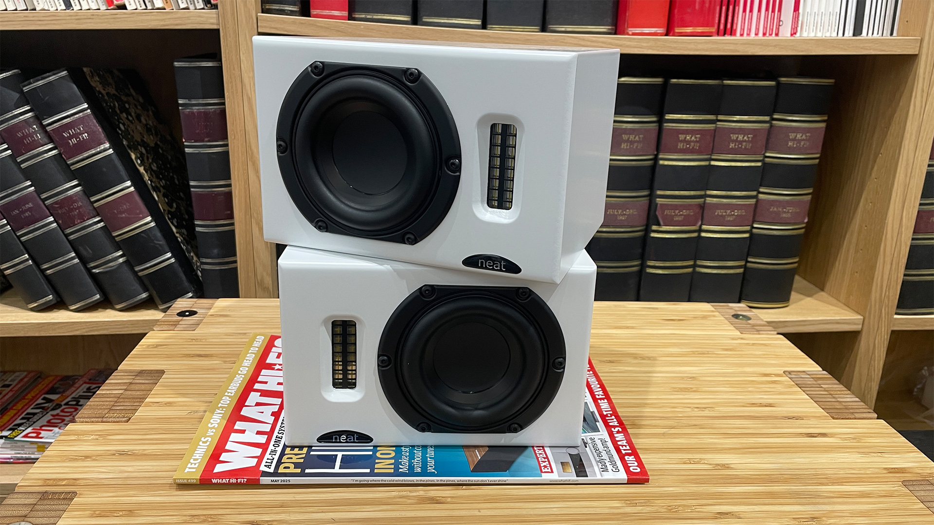 Neat Iota II speakers stacked on top of each other, placed on top of a What Hi-Fi? magazine