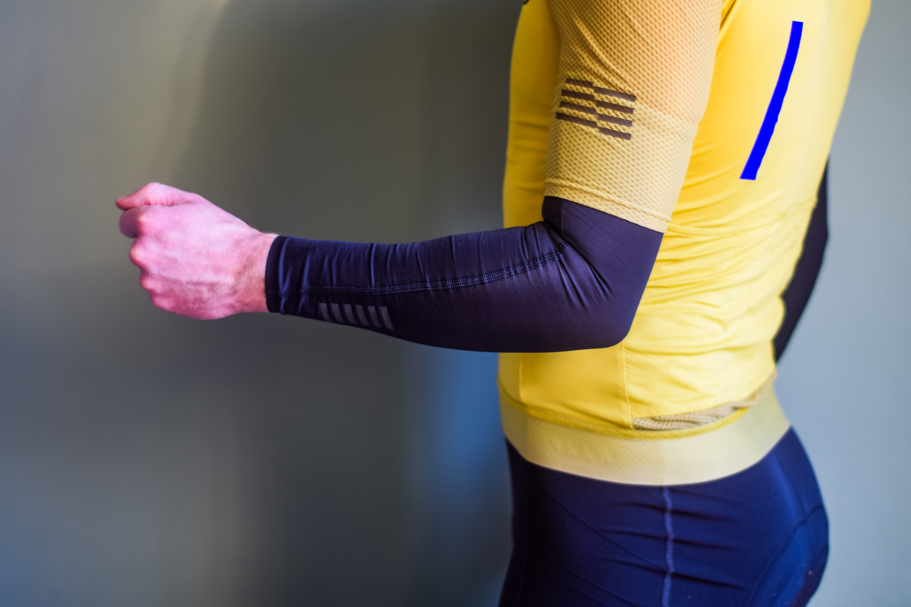 A man in a yellow cycling jersey wearing black arm warmers