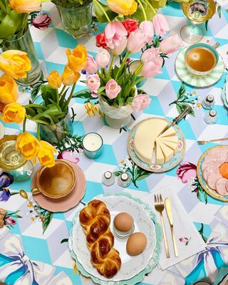 Sunny fresh floral display on colorful tablecloth pentiful of sweet treats and beautiful tableware