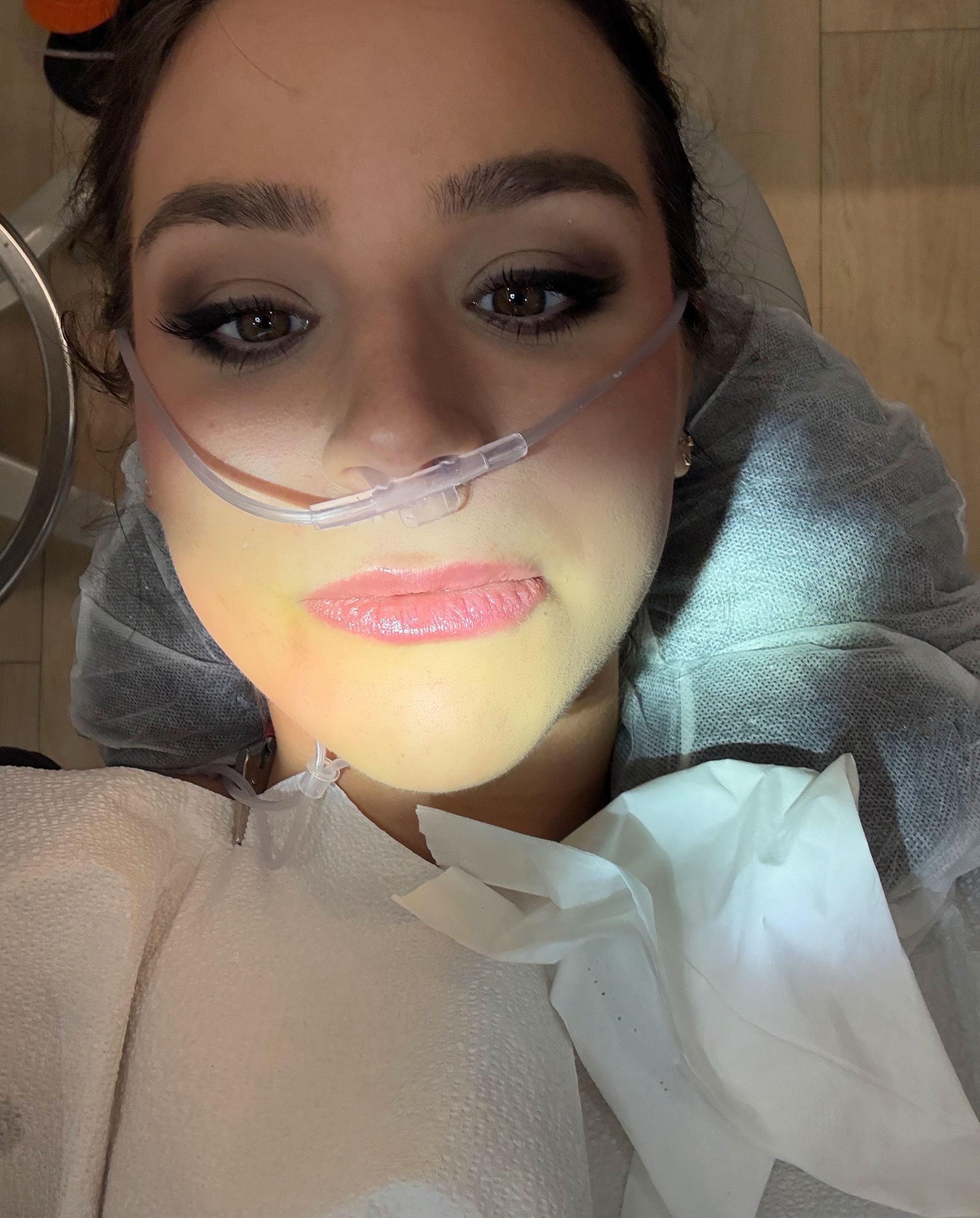 siena gagliano wearing a gray sweatshirt with a laughing gas tube in her nose