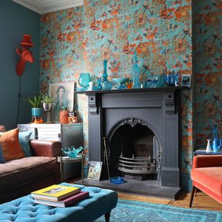 living room with traditional cast iron firplace, wallpapered feature wall and teal and orange accessories