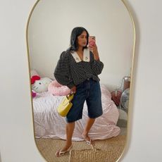 Chiara in dark, long denim shorts with yellow bag