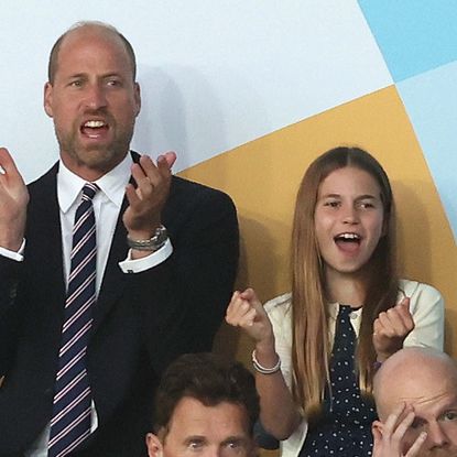 Prince William wears a suit with a red, white, and blue striped tie, and daughter Princess Charlotte wears a navy and white polka dot dress, as the pair attend the UEFA Women's Championship in Switzerland