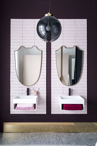A double vanity, with double mirrors with a single, modern pendant in the middle