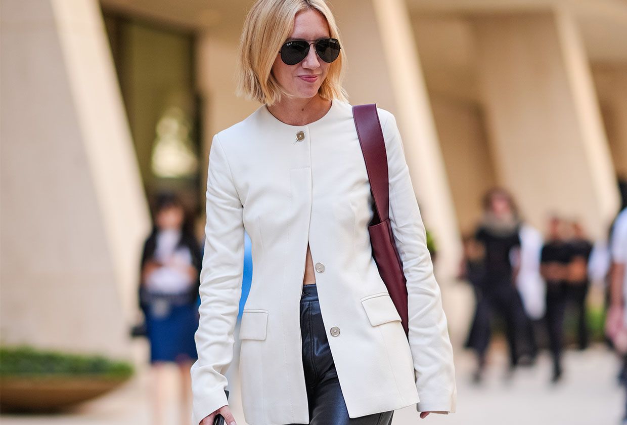 Woman in white collarless blazer, burgundy bag, and black pants