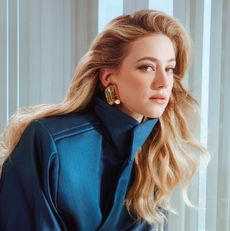 Lili Reinhart wearing a blue jacket and gold earrings