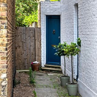 Blue front door of a brick house down a side alleyway