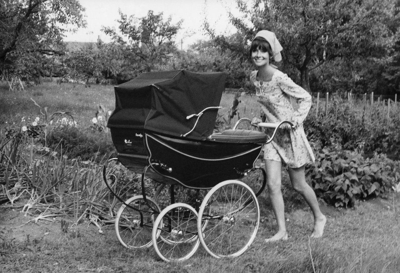 Black and white photo of Audrey Hepburn pushing a pram