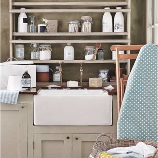 Utility room, butler belfast sink, storage shelves, assorted storage jars storing wooden dolly pegs and cleaning products