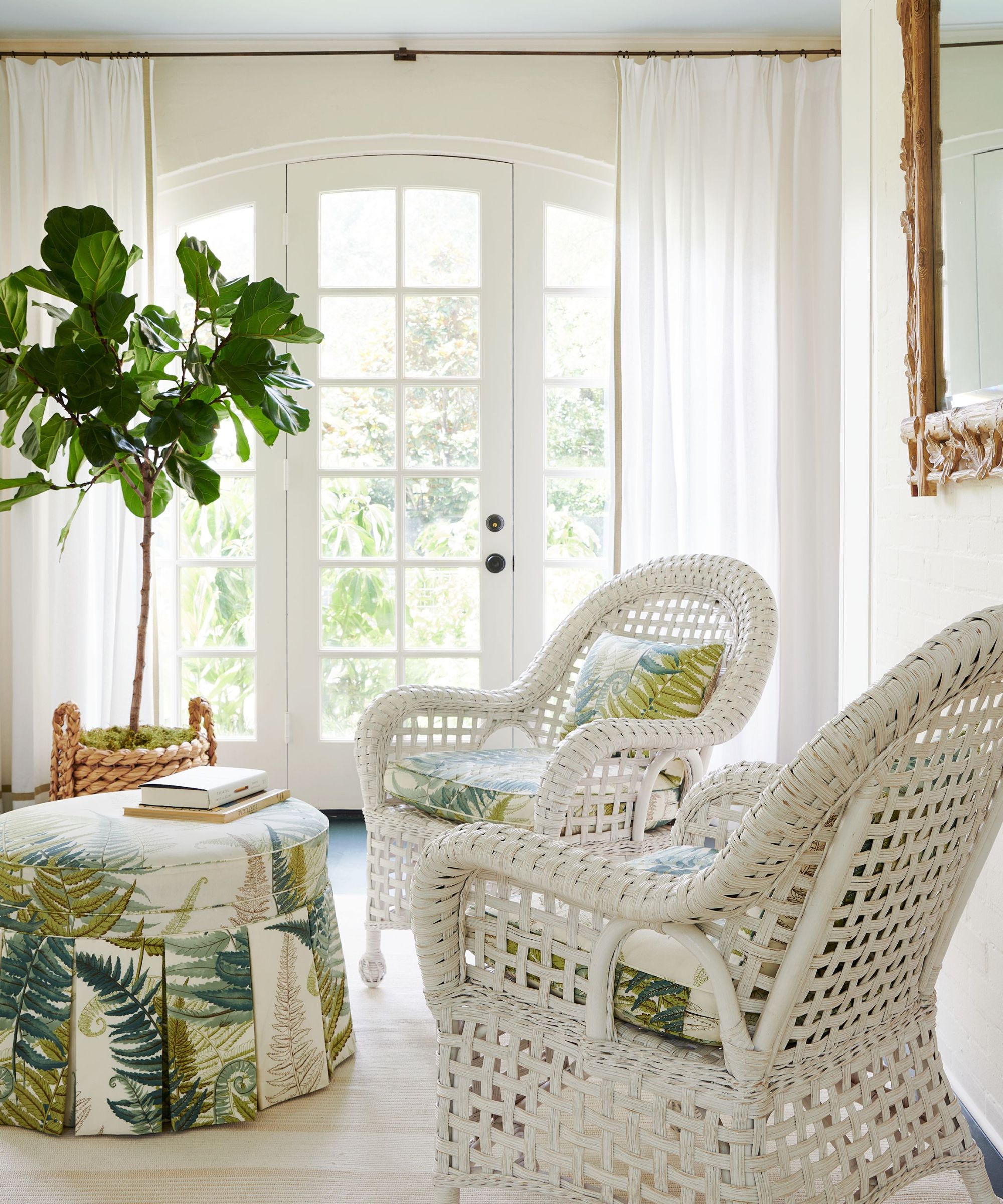 sun room with white cane chairs and round ottoman