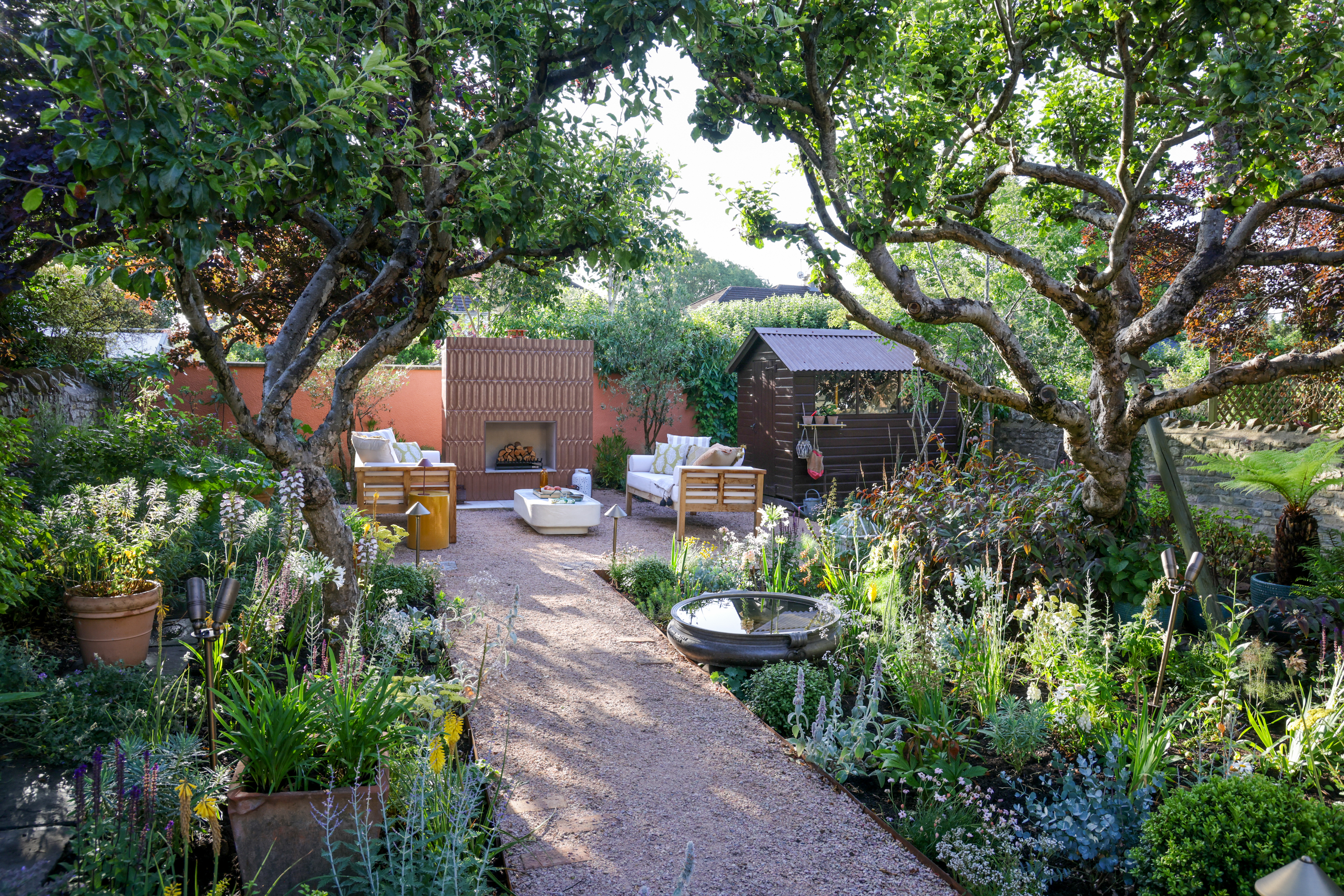 beautiful, fairytale garden with gravel paving, wild plants and a sitting area with an outdoor fireplace