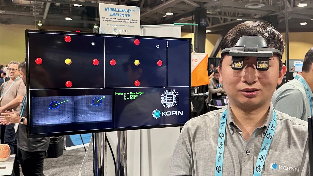 Photo of an engineer wearing the Kopin NeuralDisplay prototype OLED in front of a display showing its eye tracking in action