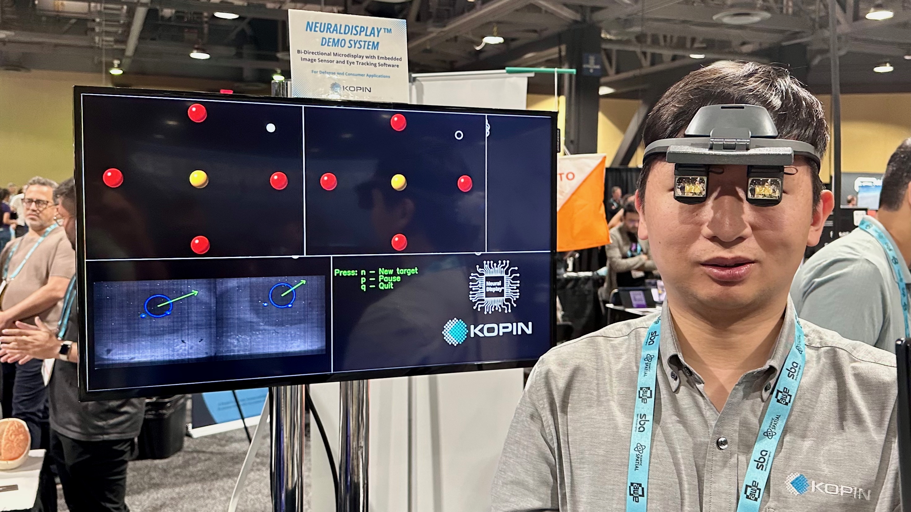Photo of an engineer wearing the Kopin NeuralDisplay prototype OLED in front of a display showing its eye tracking in action
