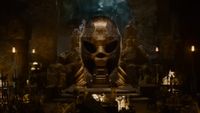 a golden skull-shaped statue in a room full of treasure