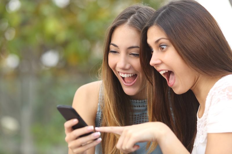 Two friends look at a phone together.