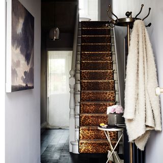 staircase with leopard print stair carpet white wall and hanger stand