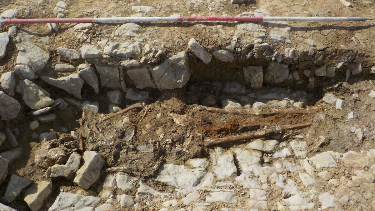 We see many stones lining the burial of a face-down skeleton.