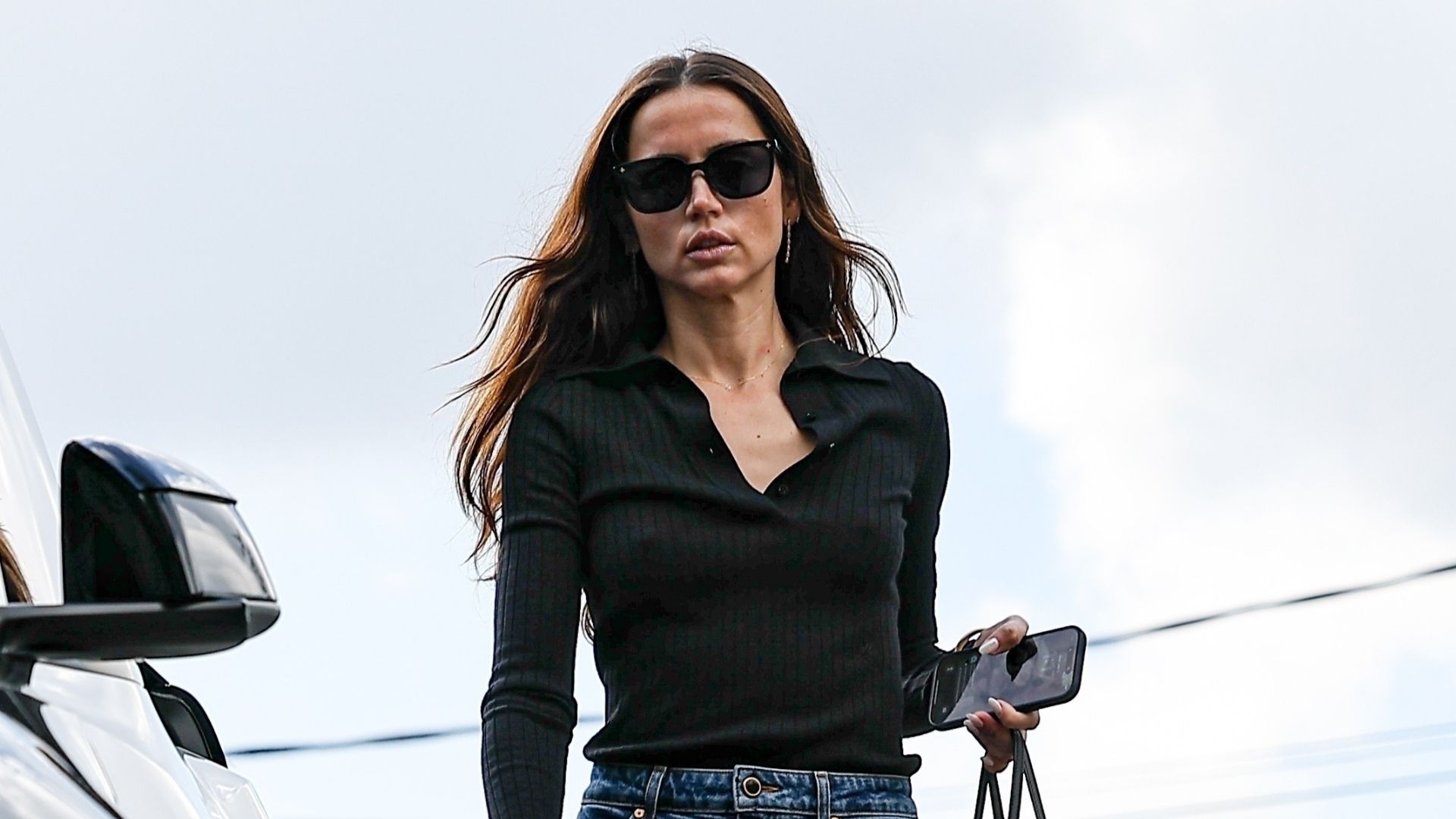 Ana de Armas wears a black long-sleeve shirt with dark blue stovepipe jeans and square-toe boots.