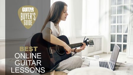 Woman sat on her bed playing an acoustic guitar in front of a laptop