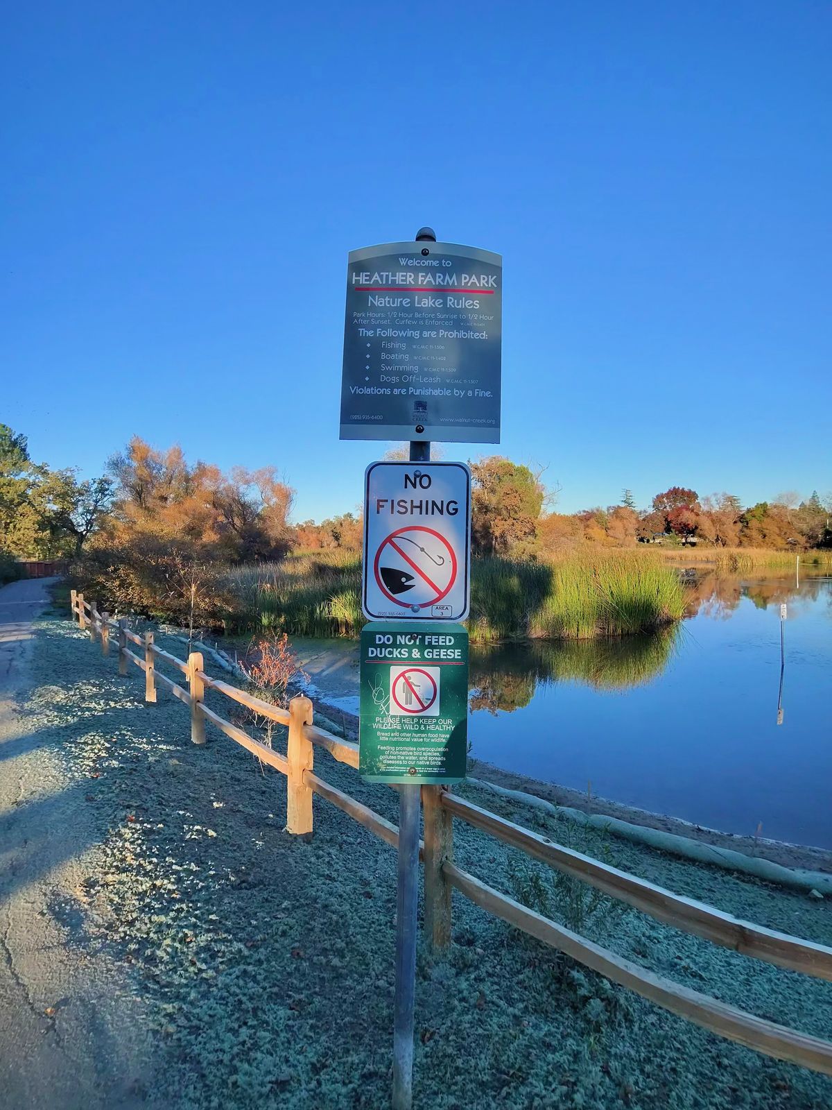 A photo taken with the Oakley Meta Vanguard smart glasses, showing park rule signs in front of a lake.