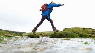 A woman wearing hiking boots while walking through a lake