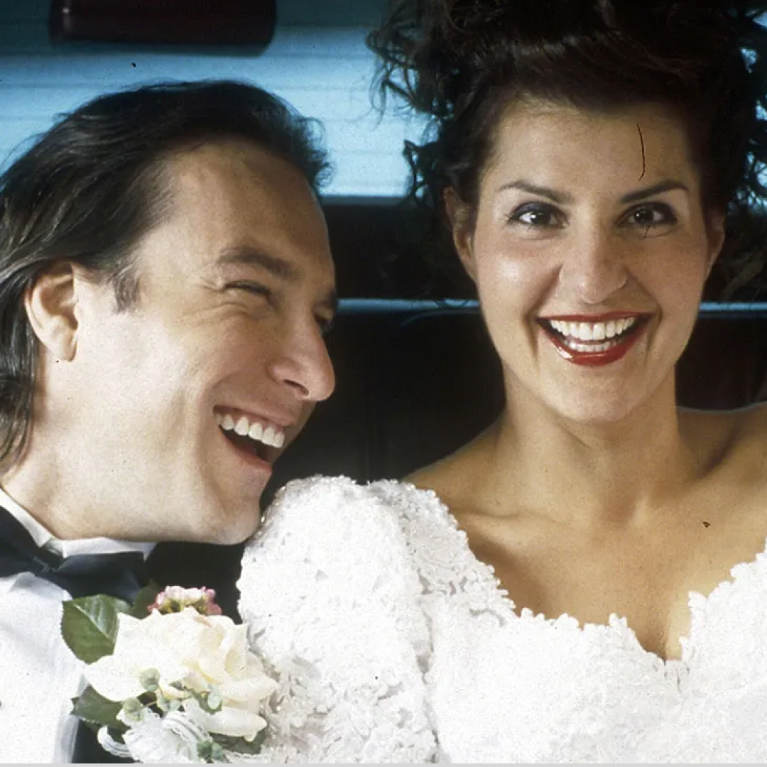 a bride and groom laugh in the back of a car in a still from my big fat greek wedding