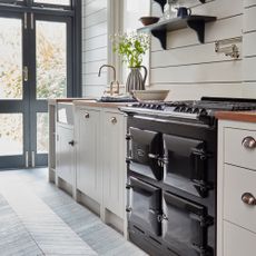 country kitchen ideas, country style kitchen with grey herringbone floor, Aga, cream Shaker style units, tongue and groove, black doors to garden, open shelving, brass tap, wood worktops 