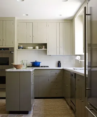 A pale green, compact kitchen with recessed spotlights