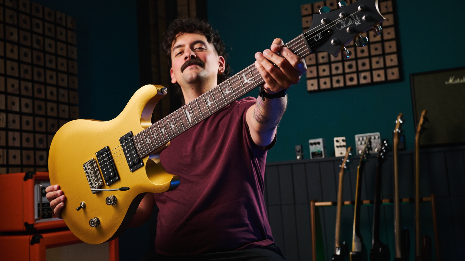 A man holding up a PRS SE CE 24 Standard Satin electric guitar