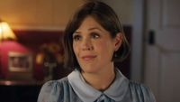 Elizabeth sitting down on the couch and looking at Nathan on When Calls the Heart.