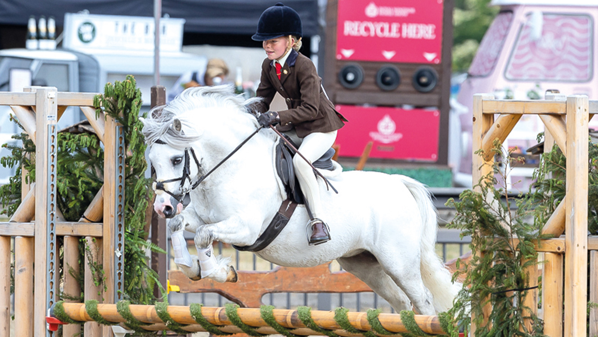Poppy Rowlands jumps M&amp;amp;M working hunter pony Delami Bravado over a rustic spread at Royal Windsor.