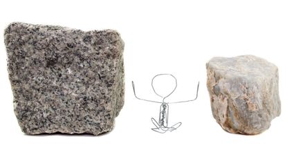 Photo illustration of a stick figure stuck between two rocks