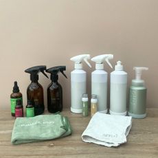 Purdy & Figg and Smol cleaning products in a line in front of a plaster pink wall
